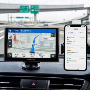 ダッシュボードに設置された高精度なカーナビゲーションと、隣に配置されたスマートフォンの地図アプリが連携して、渋滞回避ルートを表示している運転席の様子。